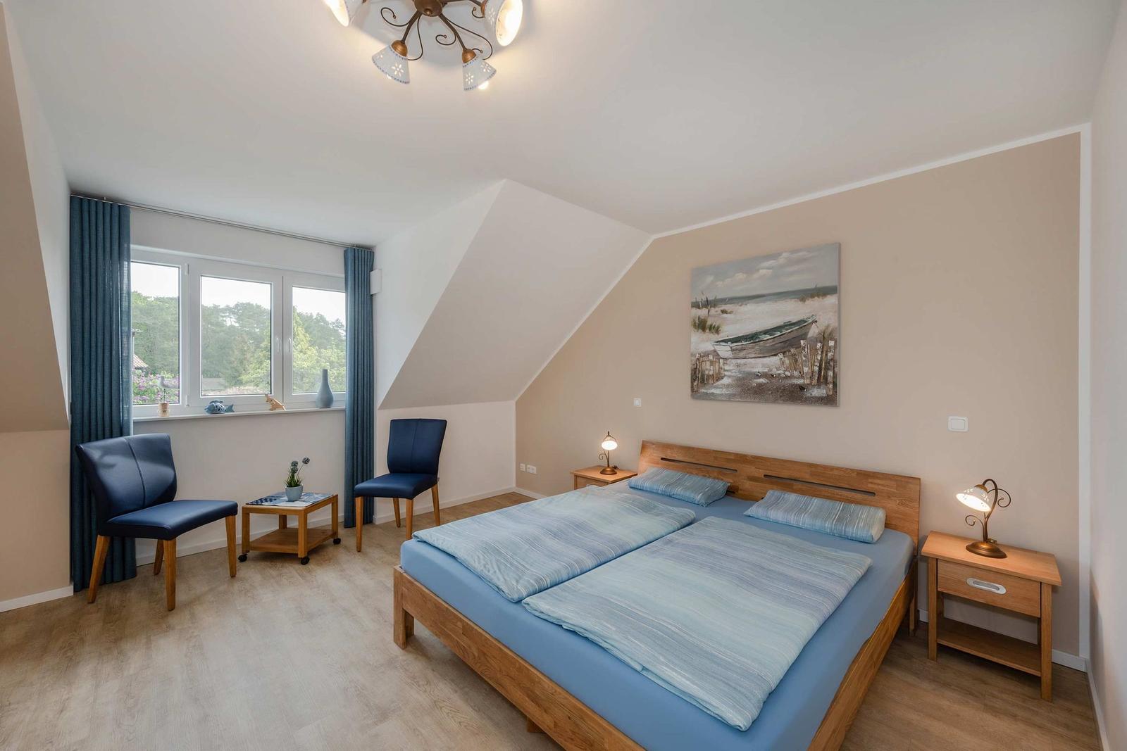 Schlafzimmer mit Doppelbett, zwei Nachttischen und Fenster mit Blick auf Grün.