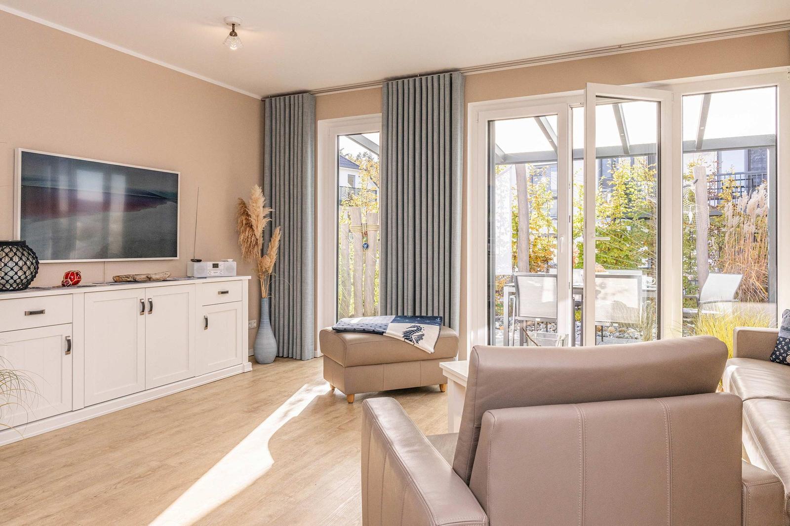 Wohnzimmer mit Sofa, Fernseher und Blick auf die Terrasse.