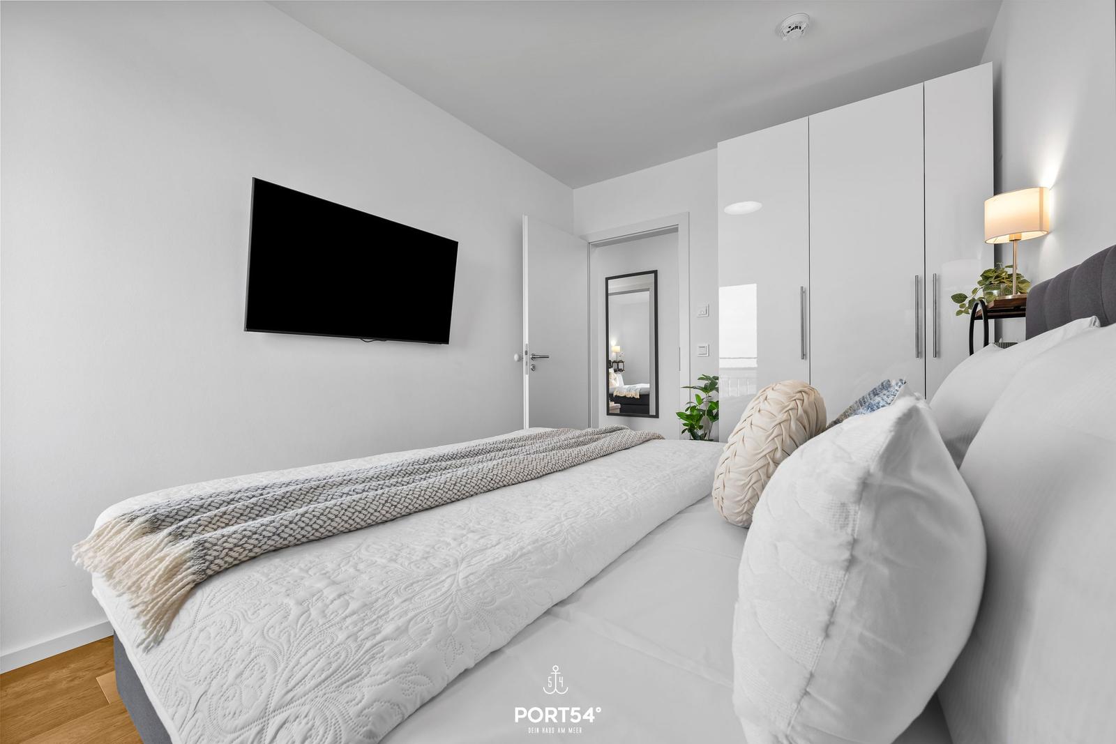 Schlafzimmer mit Bett, Fernseher und Kleiderschrank.