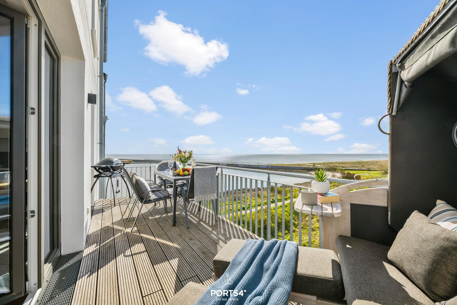 Terrasse mit Meerblick, Grill und Sitzgelegenheiten. Holzdecke und Metallgeländer.
