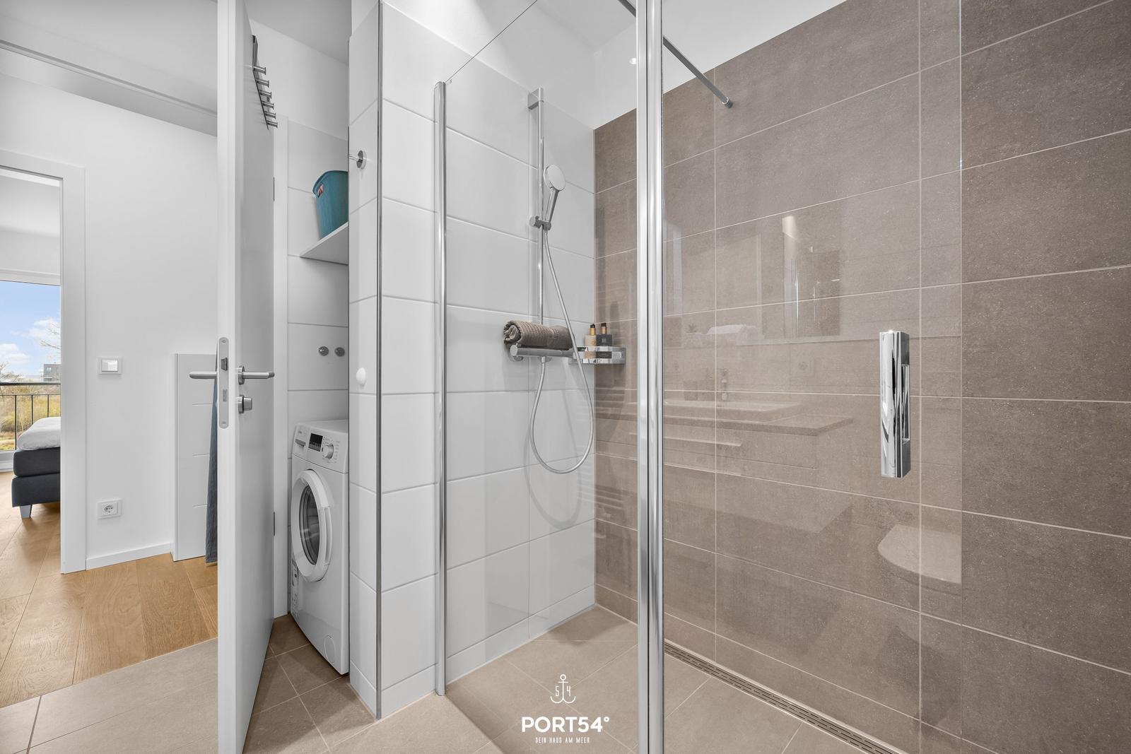 Dusche mit Glaswand, Waschmaschine und Blick in Schlafzimmer