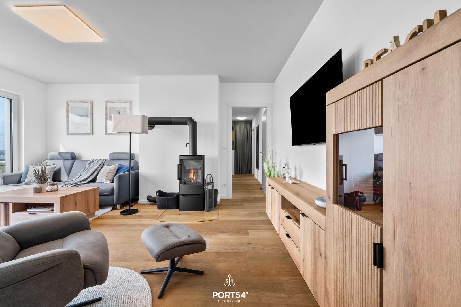 Wohnzimmer mit Holzboden, Sofa, Kamin und Fernseher an der Wand.