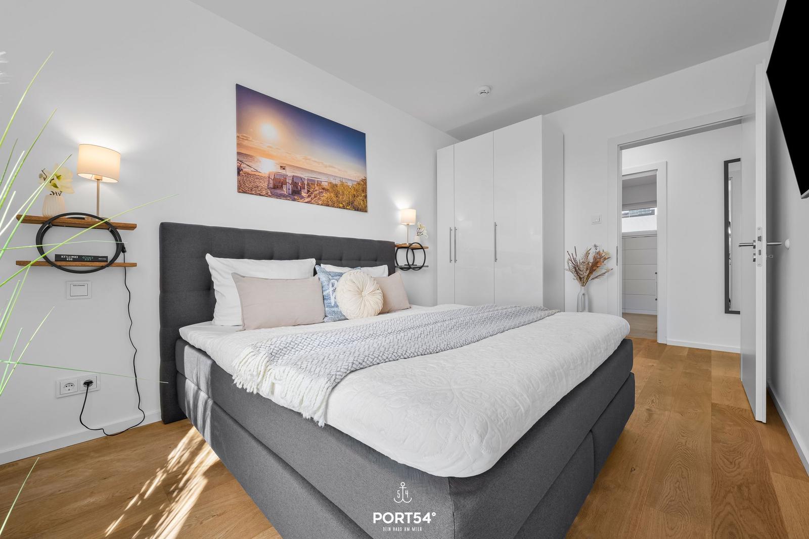 Schlafzimmer mit Doppelbett, weißen Schränken und Holzboden.
