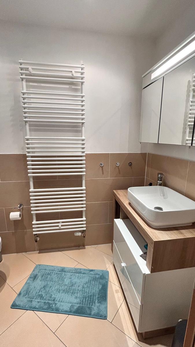 Badezimmer mit Waschbecken, Spiegelschrank und Heizkörper