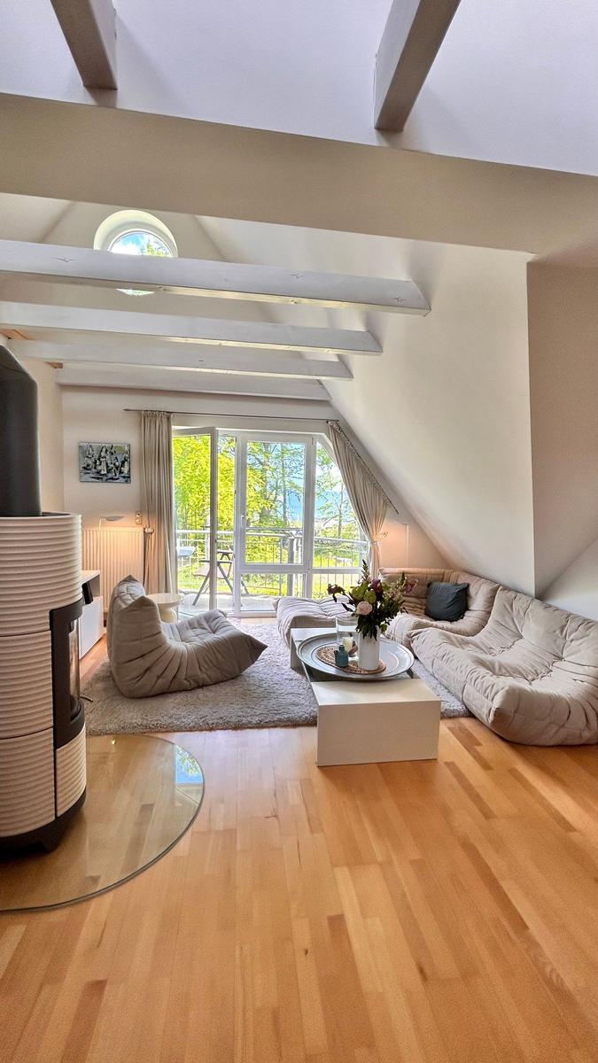 Wohnzimmer mit Holzboden, Sofa, Sitzkissen und Blick auf Balkon