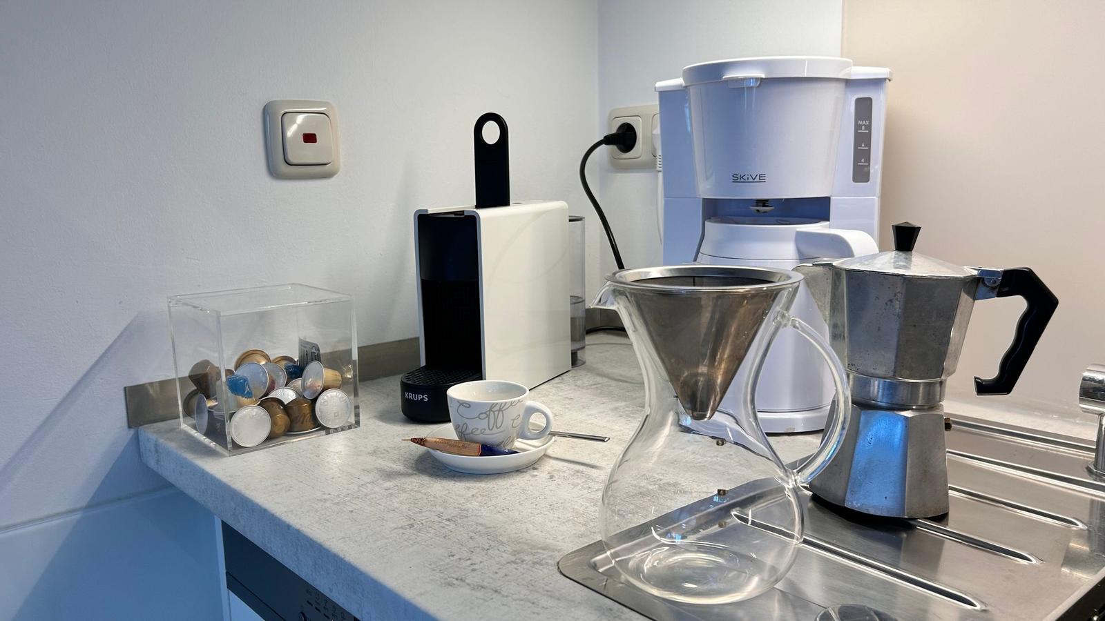 Küchenbereich mit Kaffeemaschinen und Zubehör auf Arbeitsfläche
