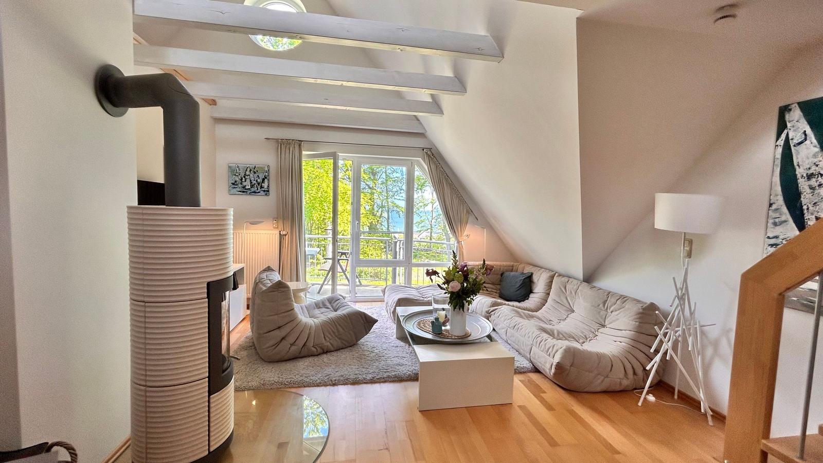 Wohnzimmer mit Sofa, Kamin und Balkonansicht