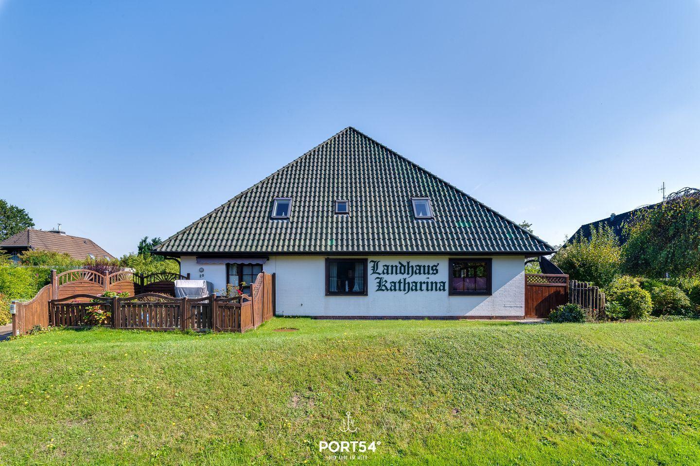 Landhaus Katharina mit grünem Garten und Holztor. Dach mit Dachfenstern.