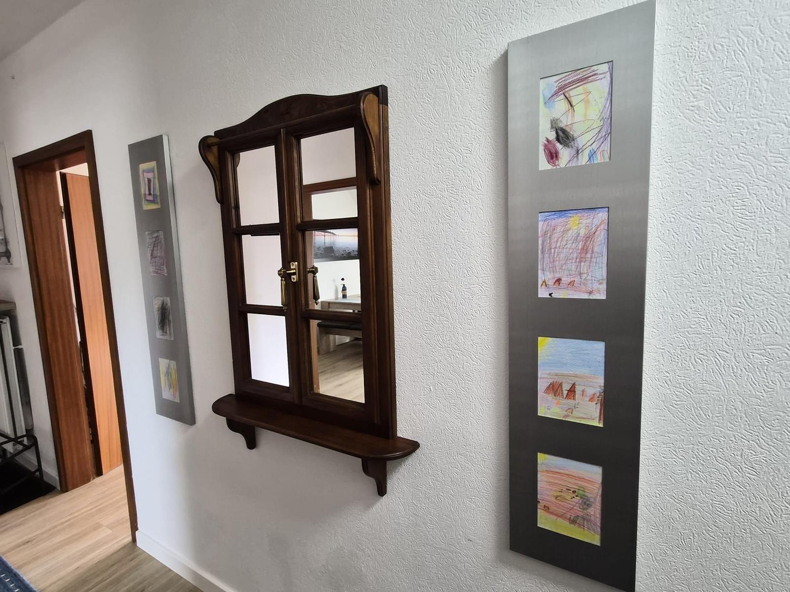 Wand mit Holzfenster und Kindergemälden in Rahmen
