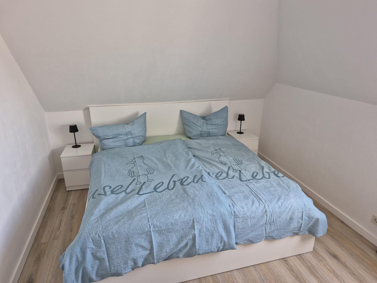 Schlafzimmer mit Doppelbett, zwei Nachttischen und Lampen.