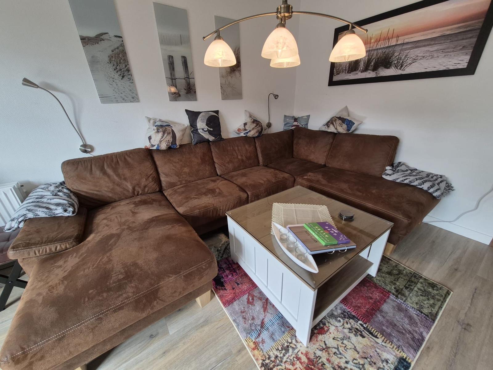 Ein Wohnzimmer mit braunem Sofa, weißem Couchtisch und Wandbildern.