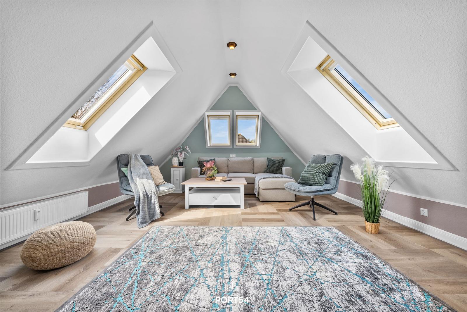 Dachgeschosswohnung mit Sitzgruppe, zwei Dachfenstern und Holzboden.