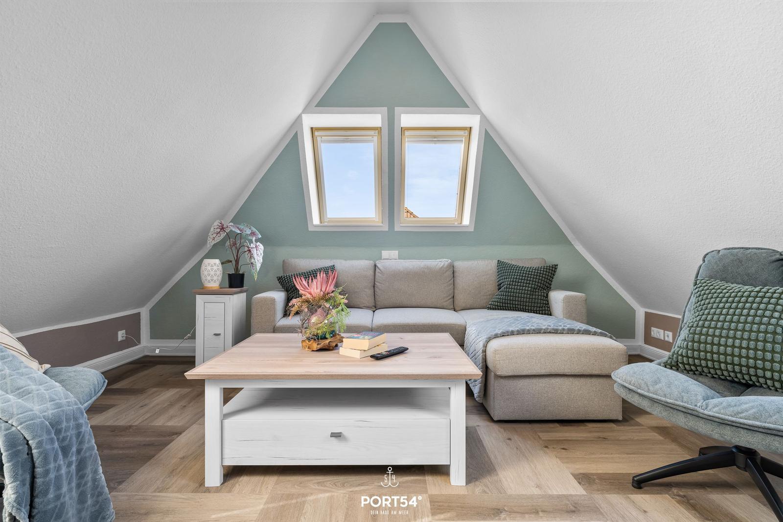 Wohnzimmer mit Sofa, Couchtisch und zwei Dachfenstern unter einem Dach