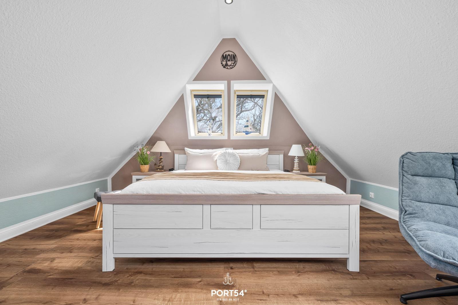 Schlafzimmer mit Dachfenstern, Bett und Sessel