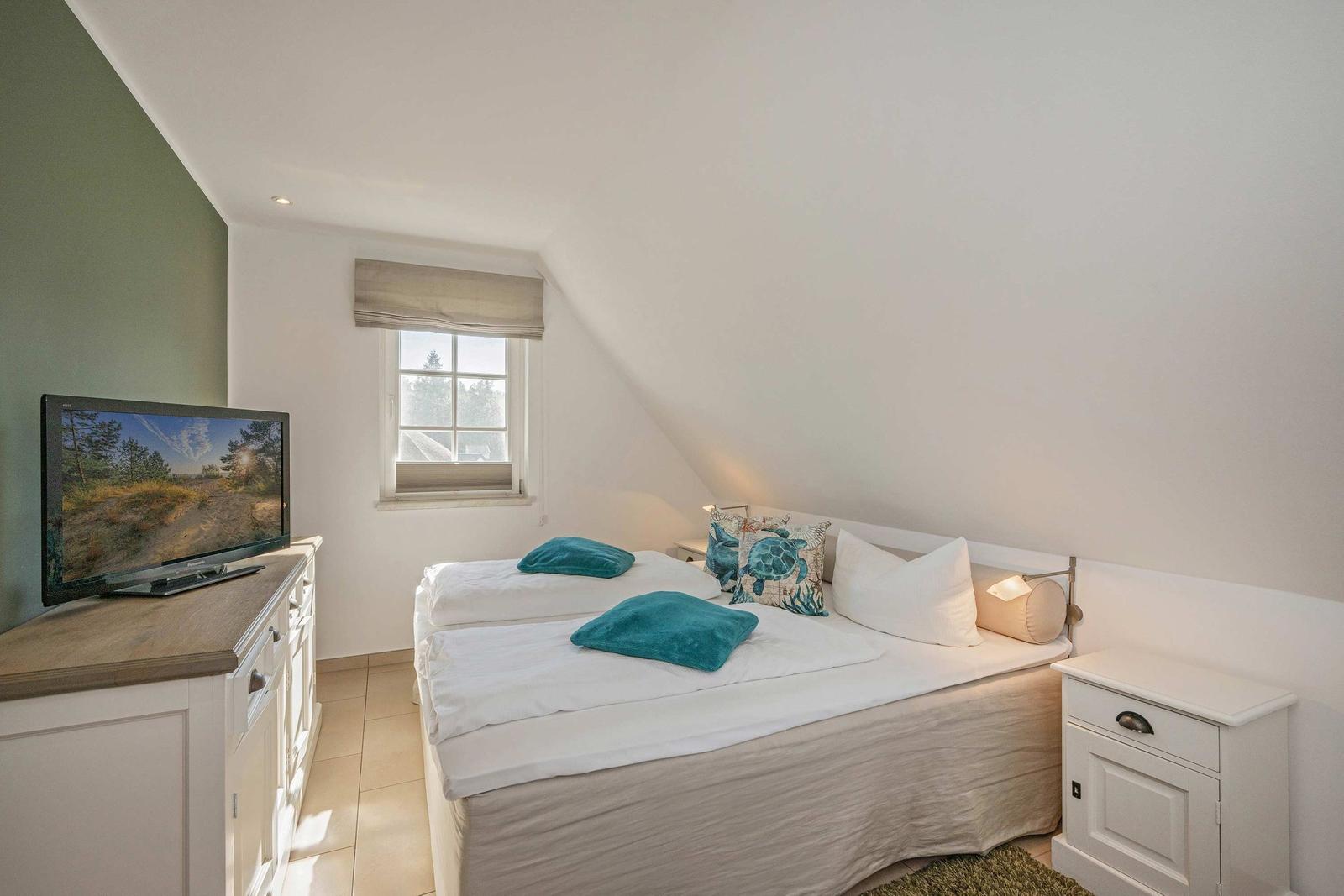 Schlafzimmer mit Doppelbett, Fernseher und Fenster mit Blick nach draußen.