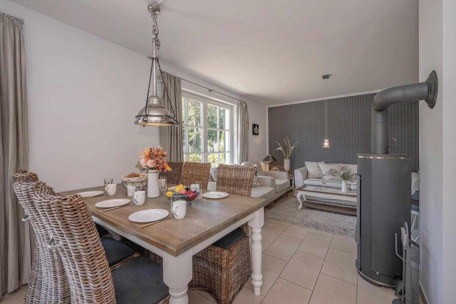 Essbereich mit Esstisch und Stühlen, Wohnbereich mit Sofa und Kaminofen.