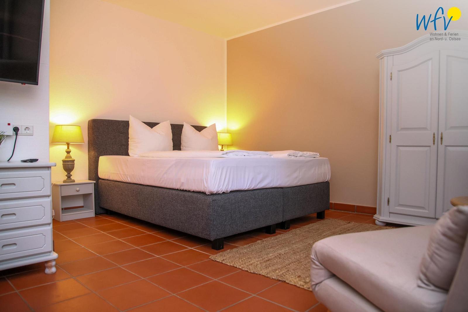 Schlafzimmer mit Bett, Nachttischen, Kleiderschrank und Fernseher.