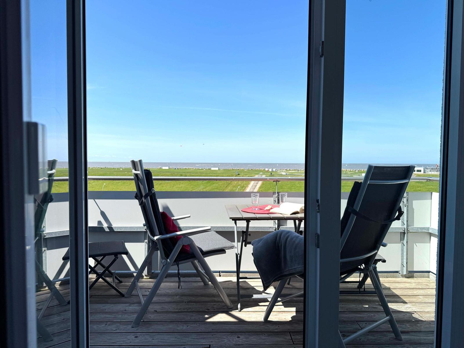 Terrace with two chairs and table. View of green field and horizon.