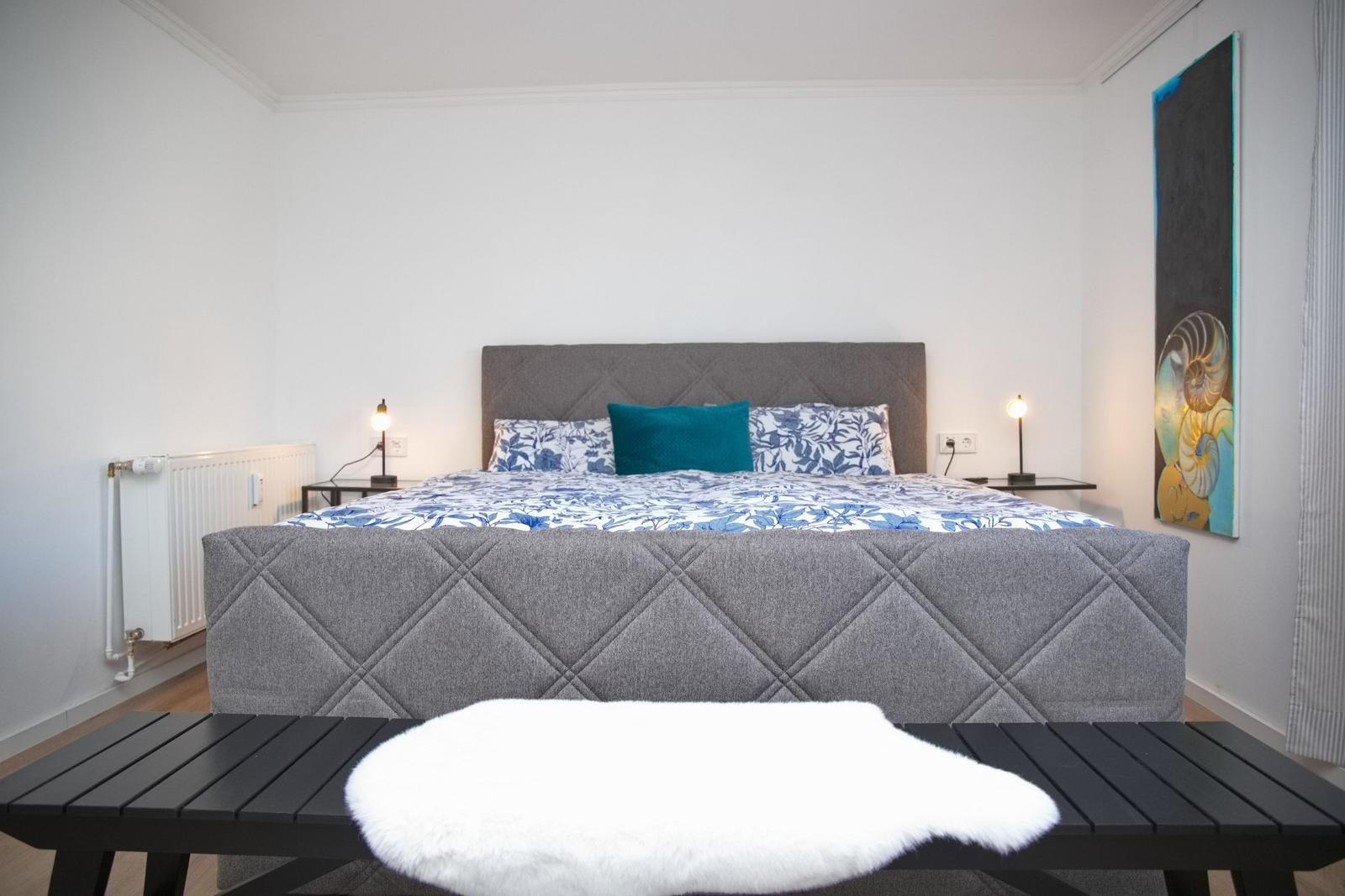 Schlafzimmer mit Bett, Nachttischen und Wandbild.