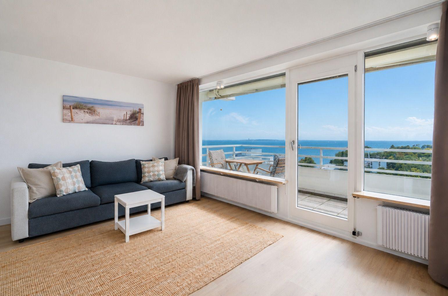 Living room with sofa, rug, and balcony view of the sea.