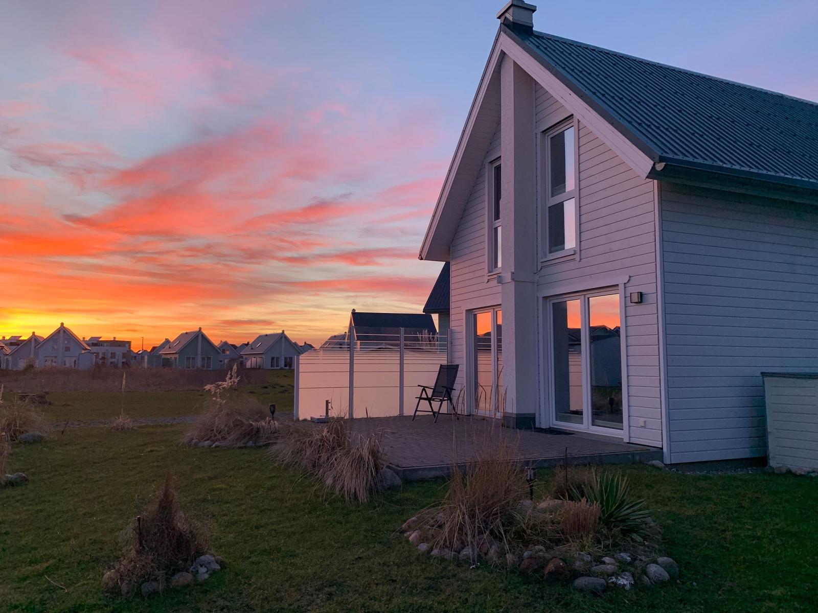 Moderne Villa mit Terrasse und Blick auf Sonnenuntergang.