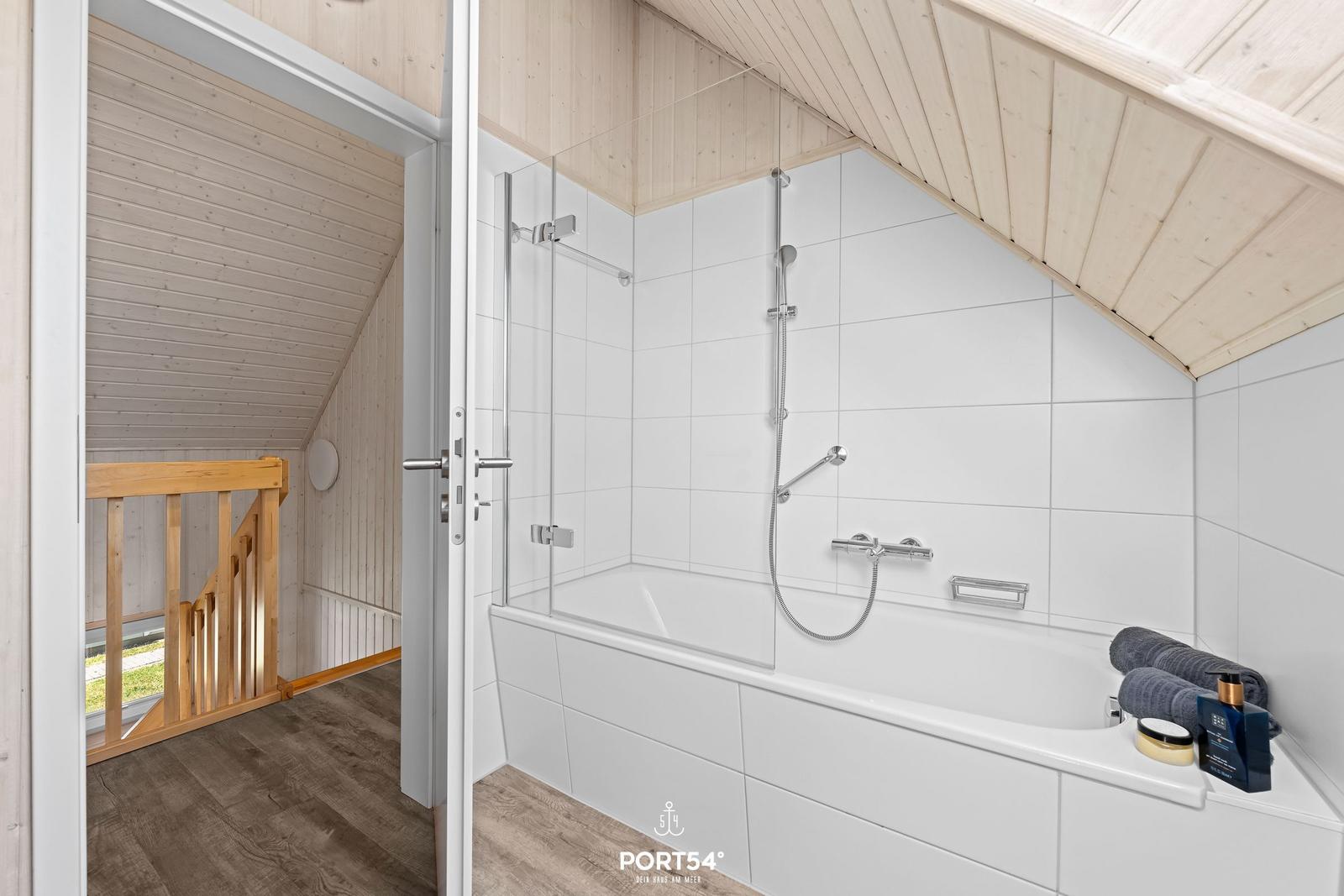 Badezimmer mit Dusche und Badewanne unter schrägem Dach