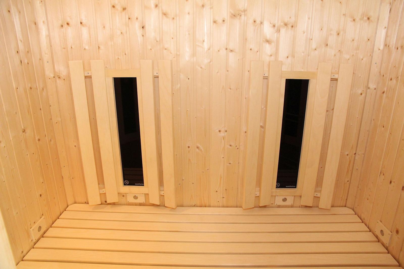 Sauna mit Holzwand und Sitzbänken. Zwei Fenster sind eingebaut.