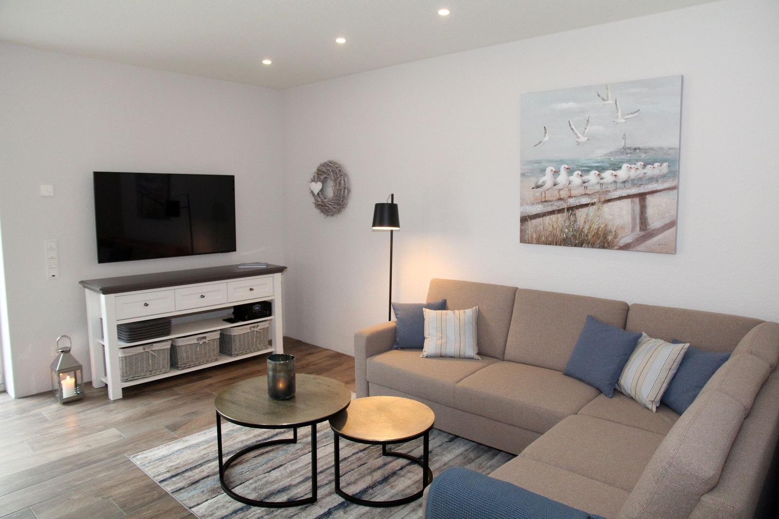 Wohnzimmer mit Sofa, Couchtisch und Fernseher an der Wand.