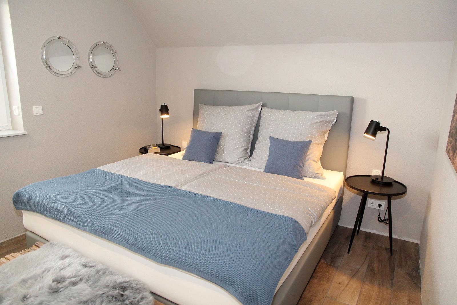 Schlafzimmer mit Doppelbett, zwei Nachttischen und zwei runden Spiegeln an der Wand.