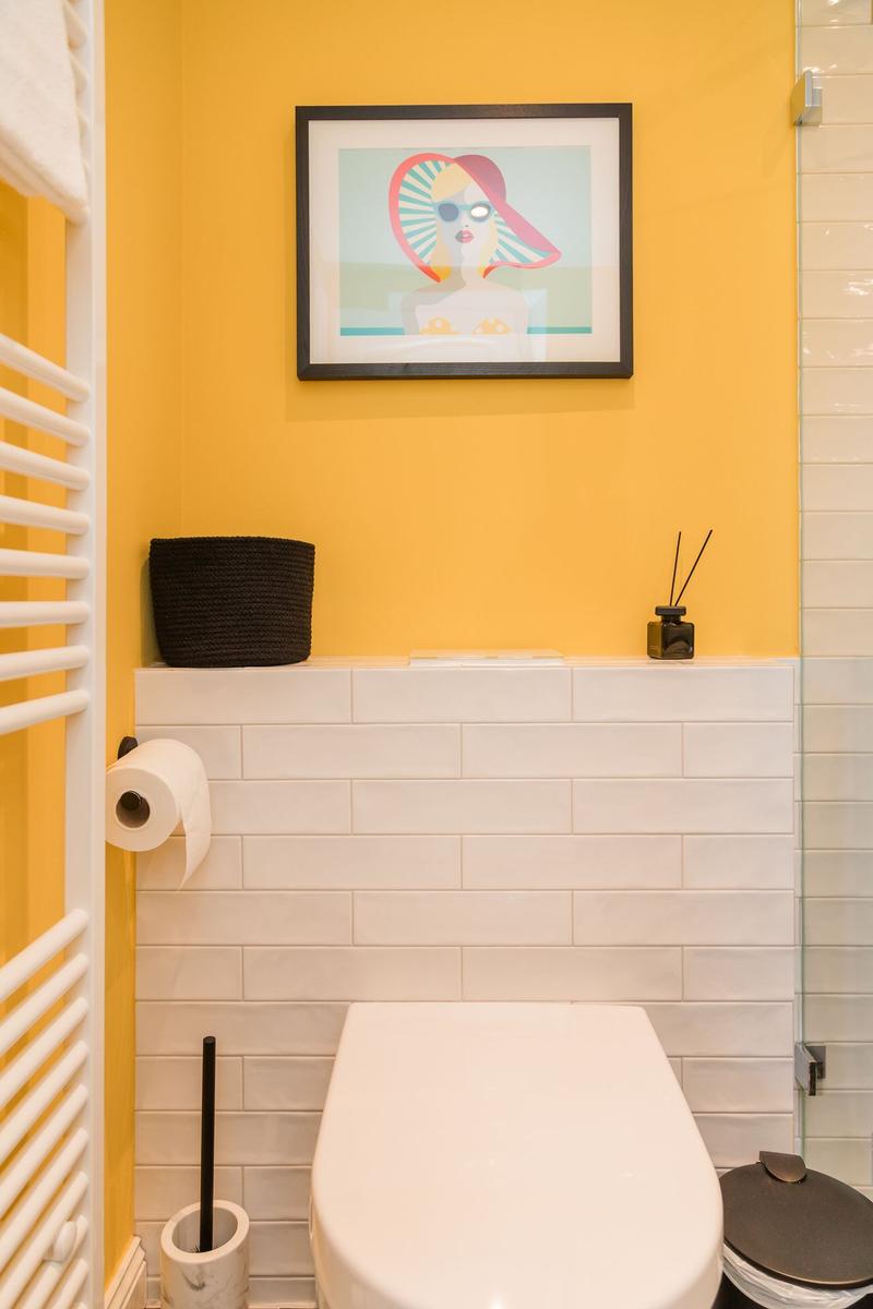 Badezimmer mit gelber Wand, Toilette und Bild an der Wand.