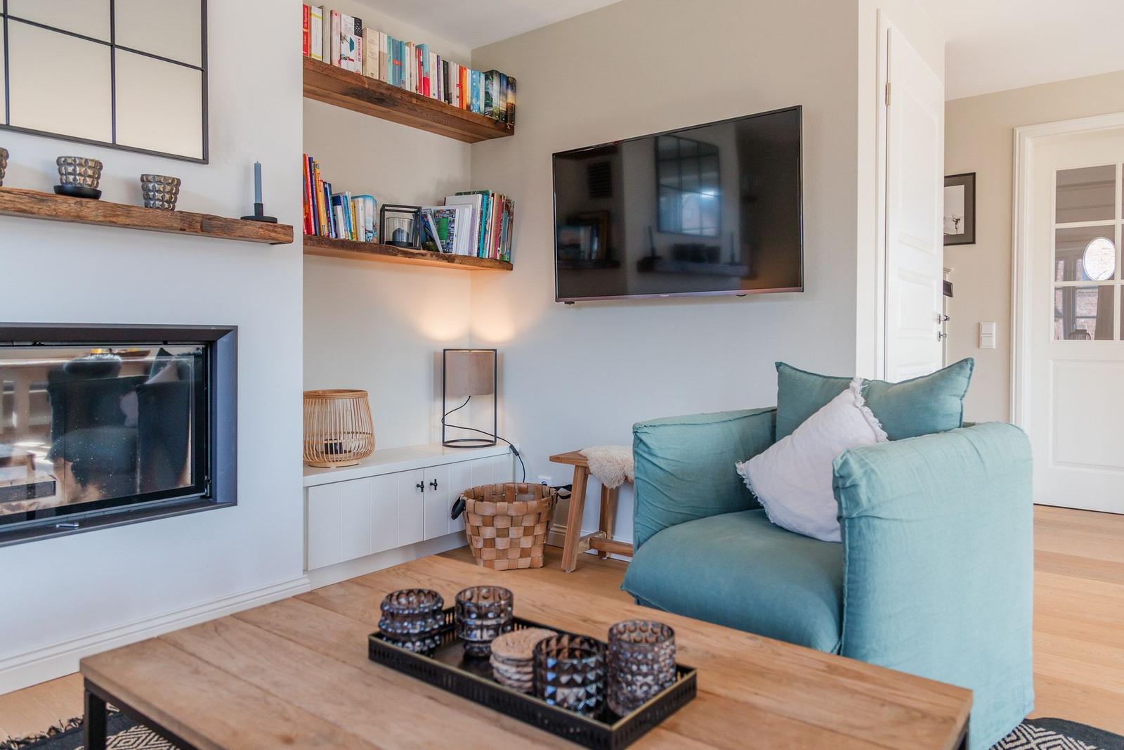 Wohnzimmer mit Sofa, Fernseher, Kamin und Holztisch.
