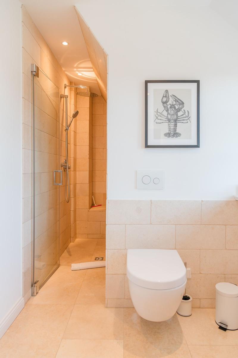Badezimmer mit Dusche, Toilette und Wandbild von Hummer.