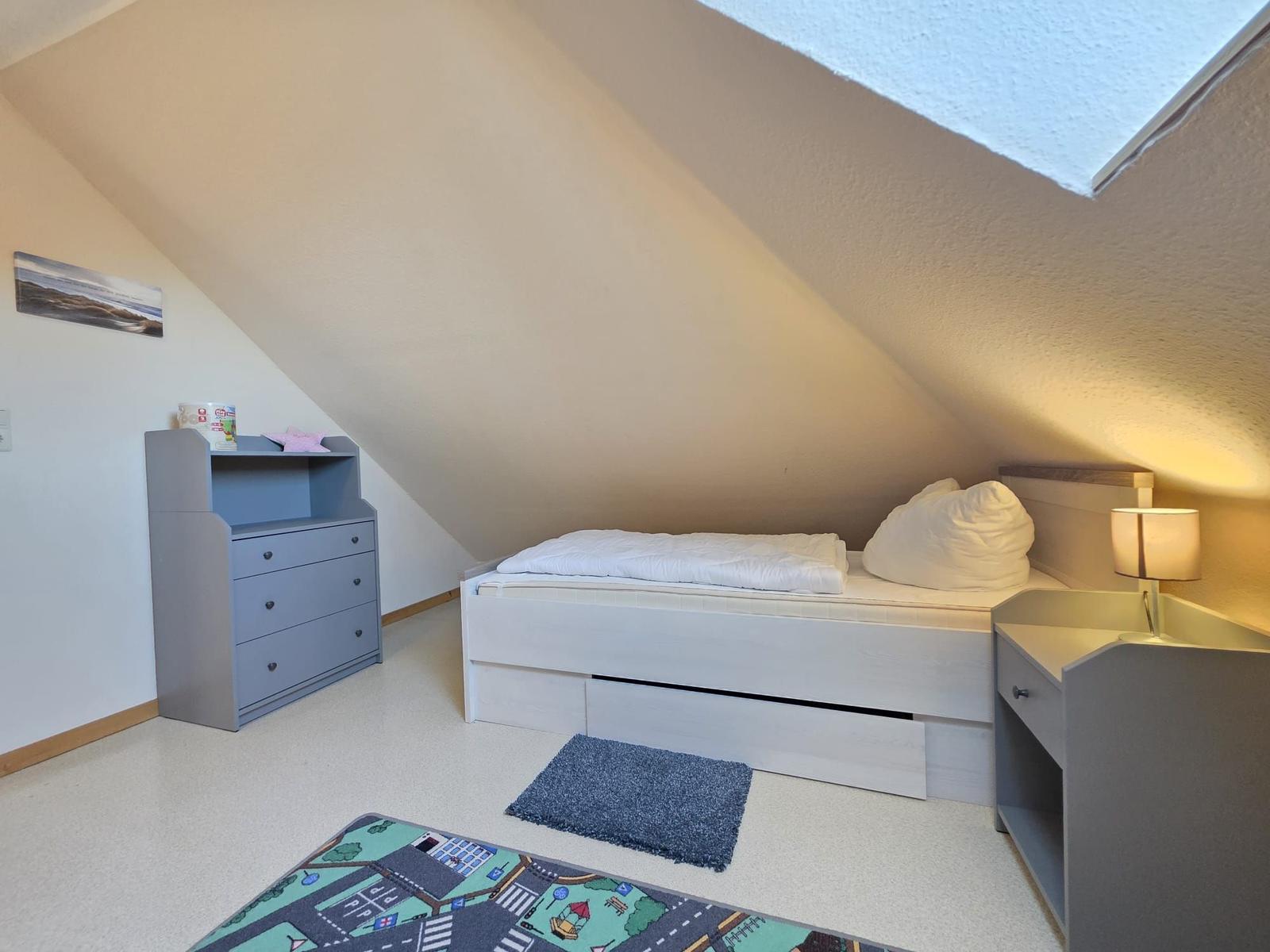Schlafzimmer mit Dachschrägen, Bett, Nachttisch und Kleiderschrank.