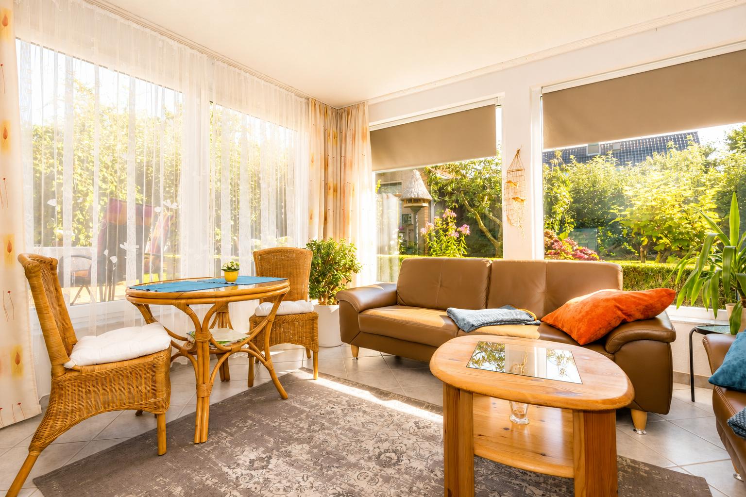 Ein Wohnbereich mit braunem Sofa, runden Tischen und Blick auf einen Garten.