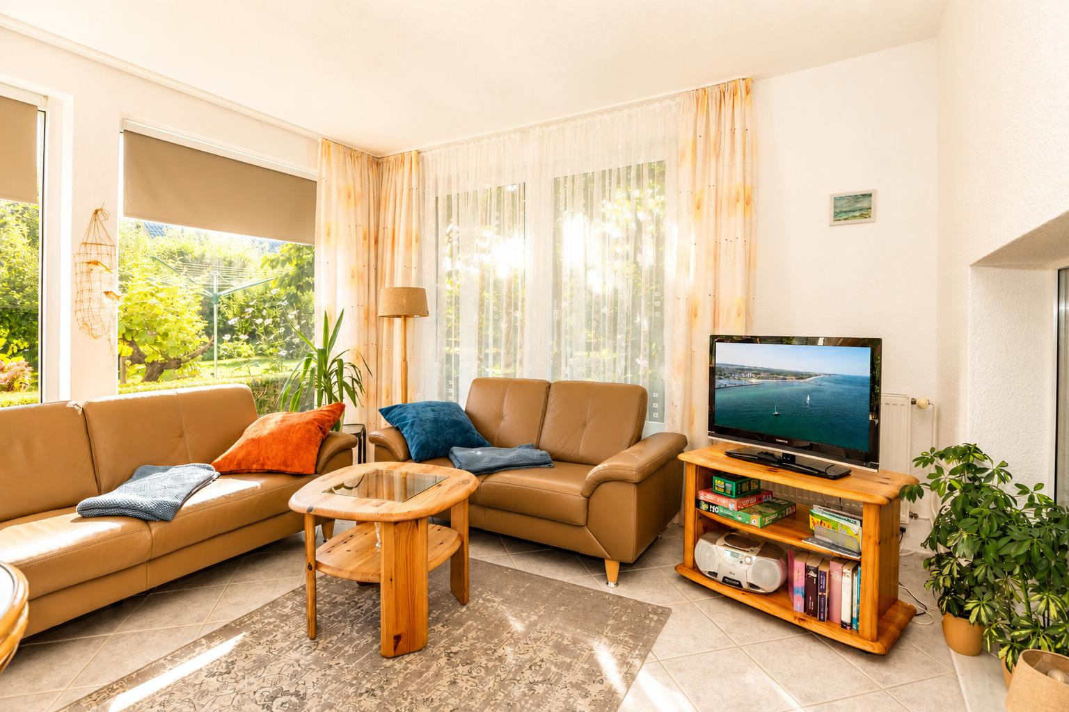 Wohnzimmer mit braunen Sofas, Holztisch und Fernseher auf Holzregal.