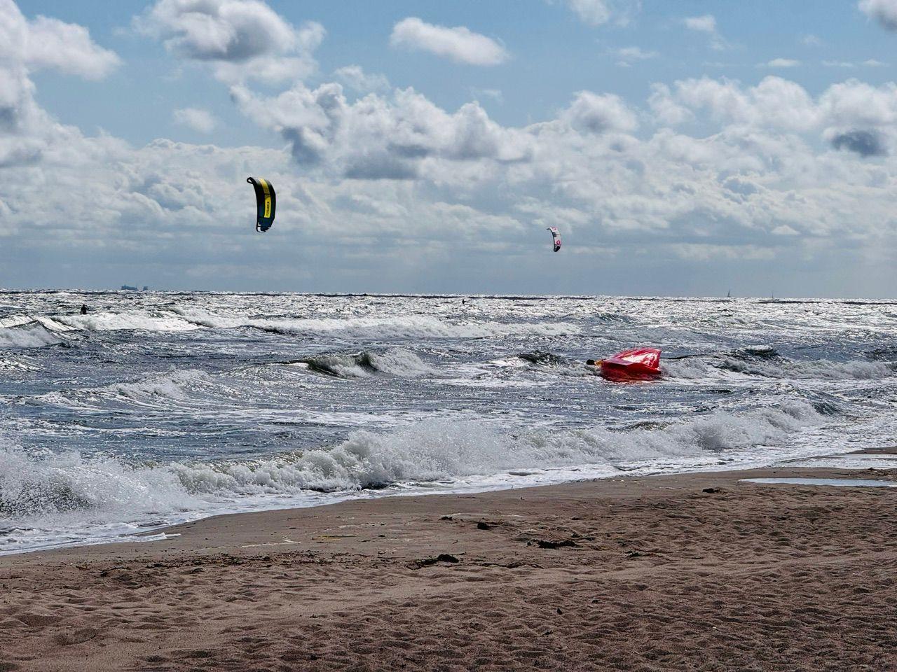 Kitesurfen am Strand mit zwei Kites über dem Meer.