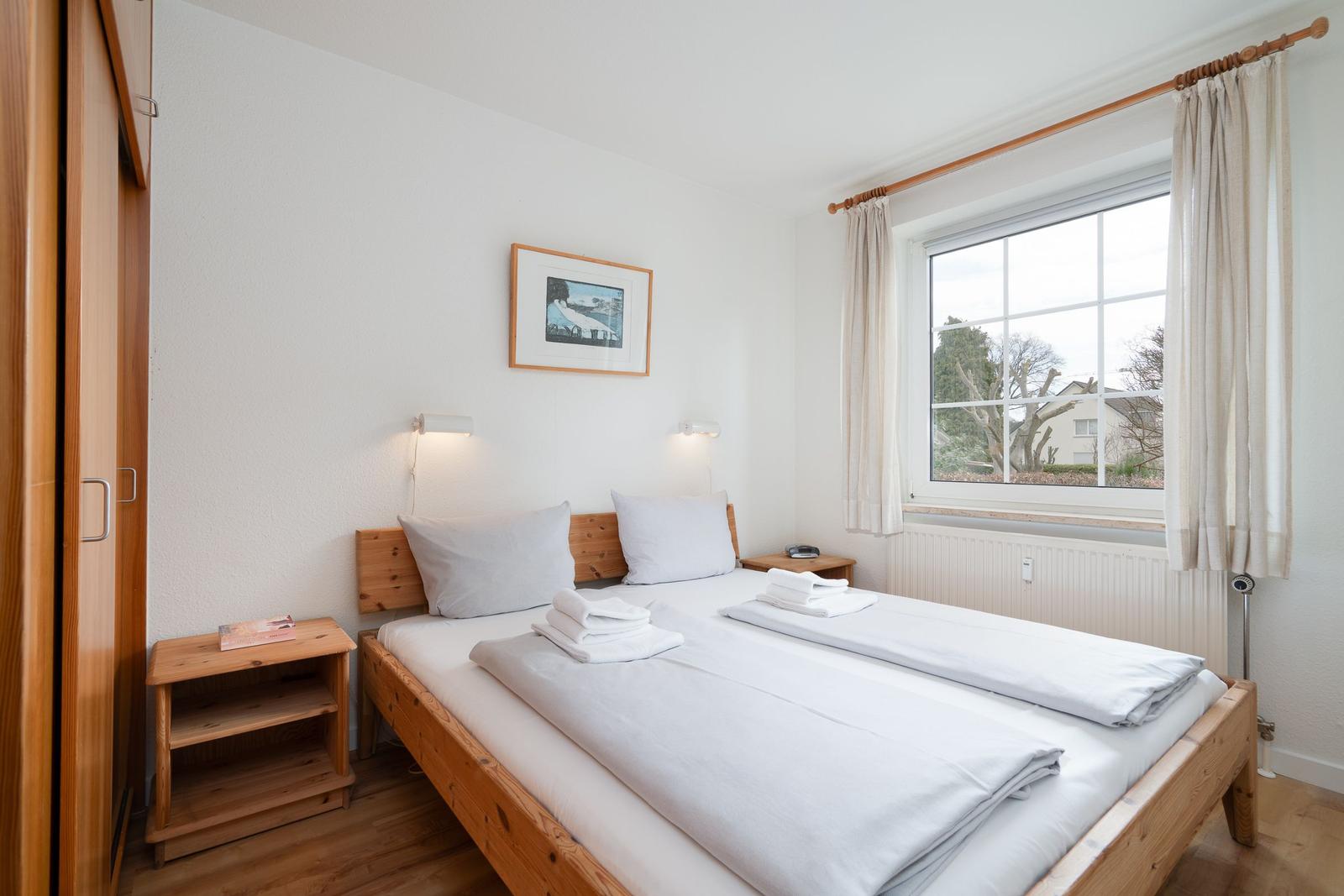 A bedroom with a bed, two nightstands, and a window.