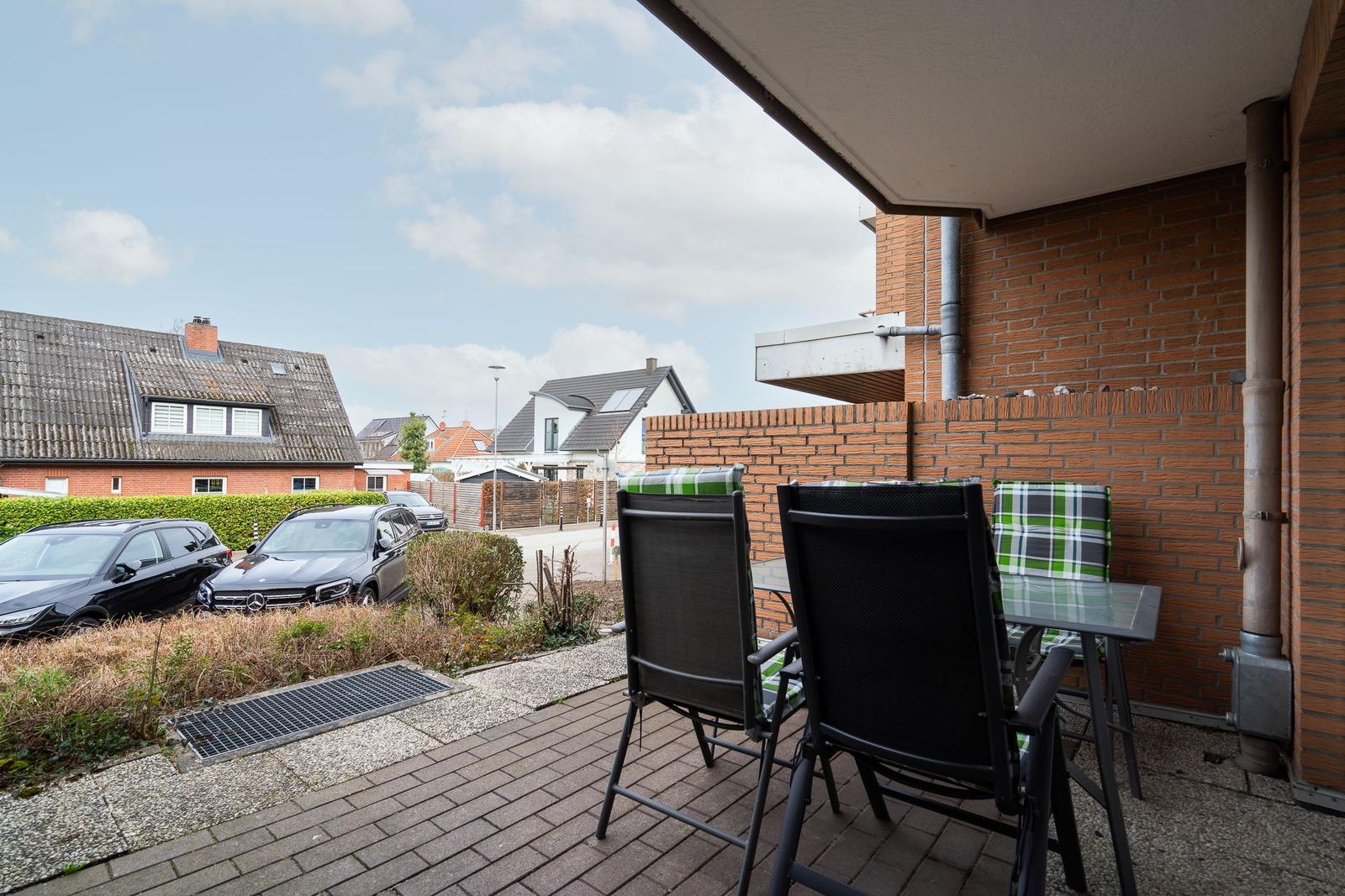 Terrace with table and chairs, view of street and neighboring houses.