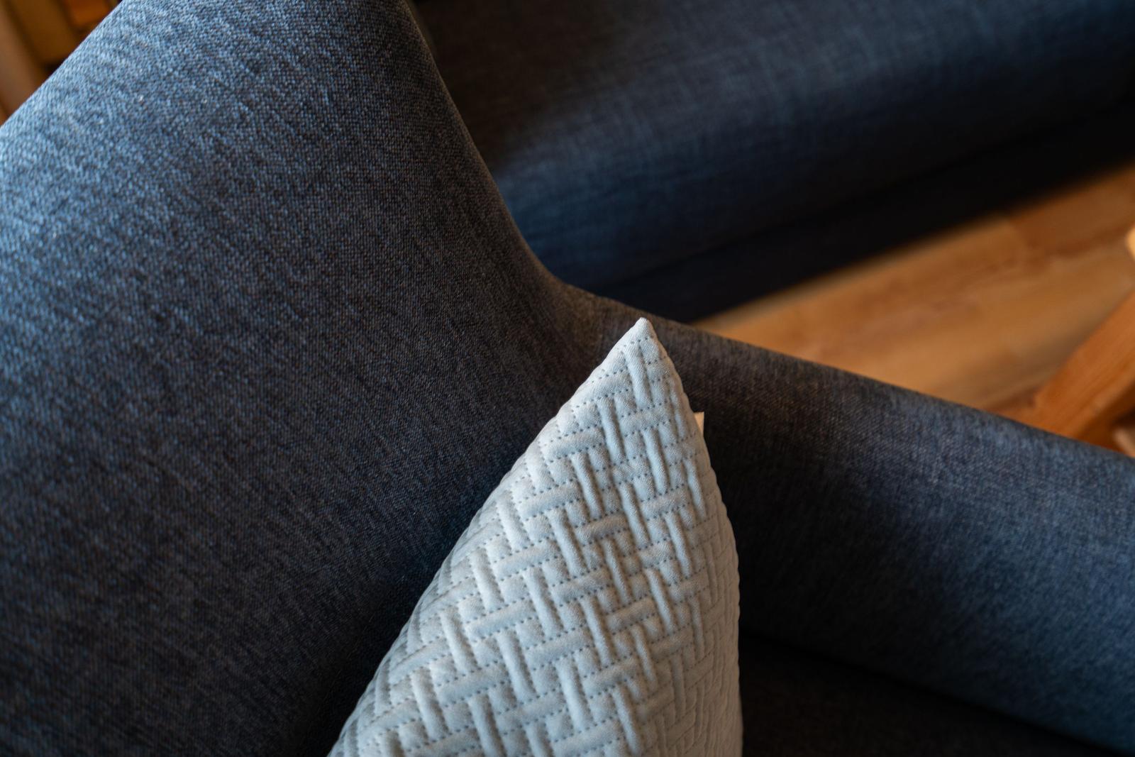 Dark blue sofa with a white pillow featuring a pattern.
