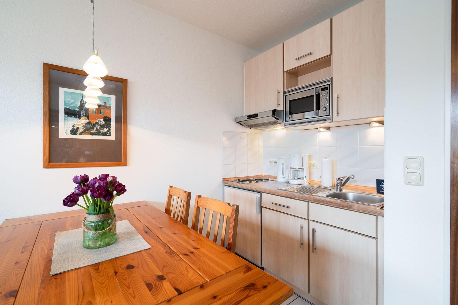 Kitchen with dining area, wooden table, microwave, and kitchen counter