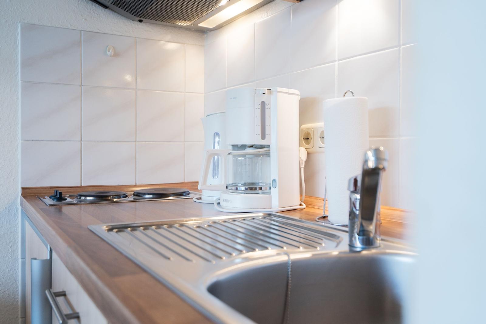 Kitchen with sink, coffee machine, and stovetop.