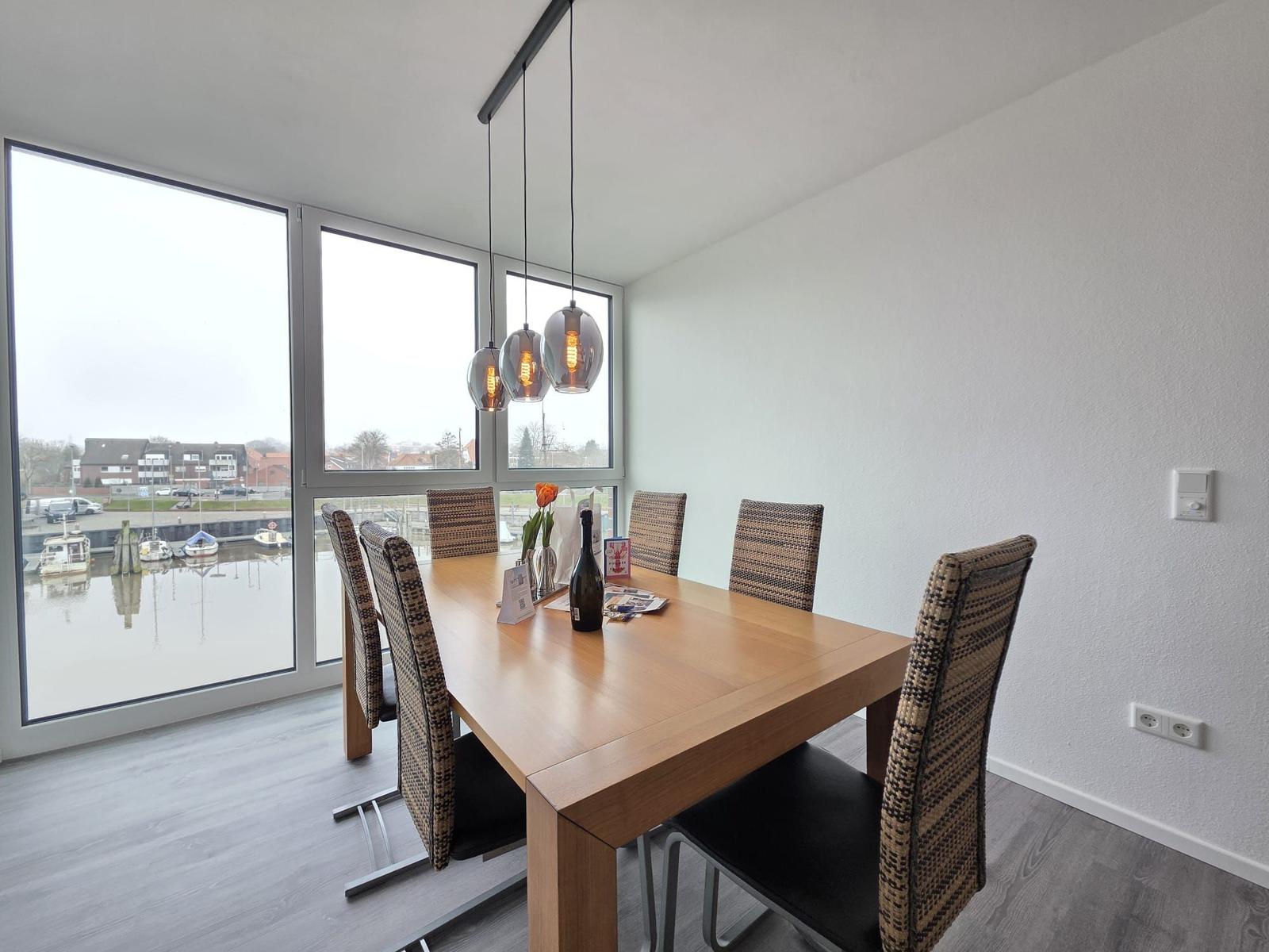 Esszimmer mit Tisch, Stühlen und Blick auf Hafen.