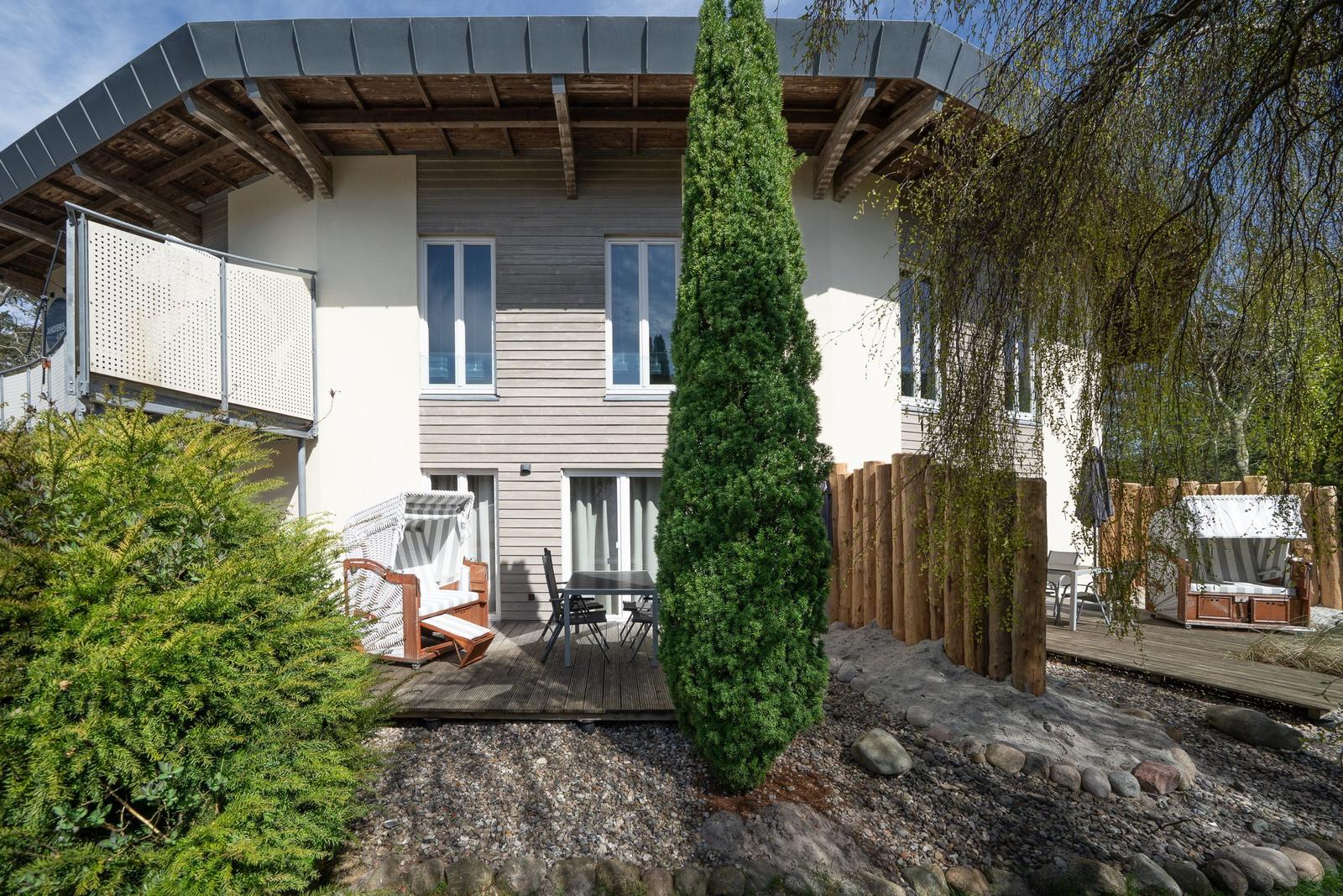 Moderne Villa mit Terrasse, Sitzgelegenheiten und umliegenden Bäumen.