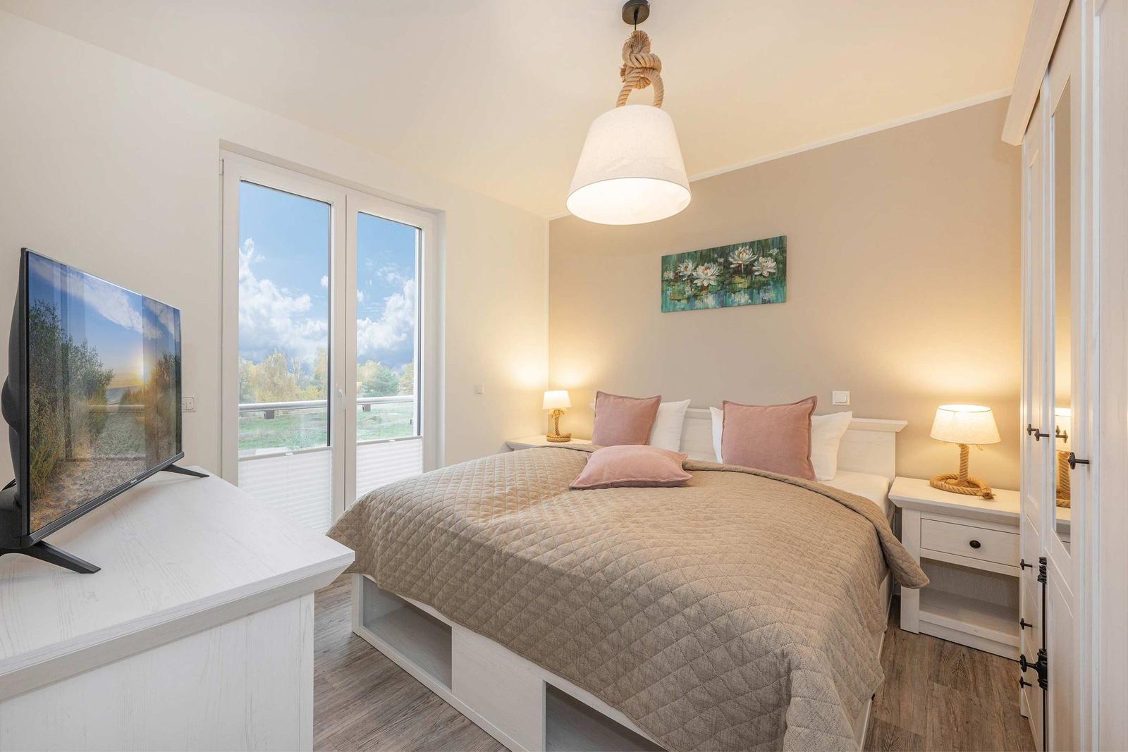 Schlafzimmer mit Bett, Fernseher und Fenster zur Aussicht