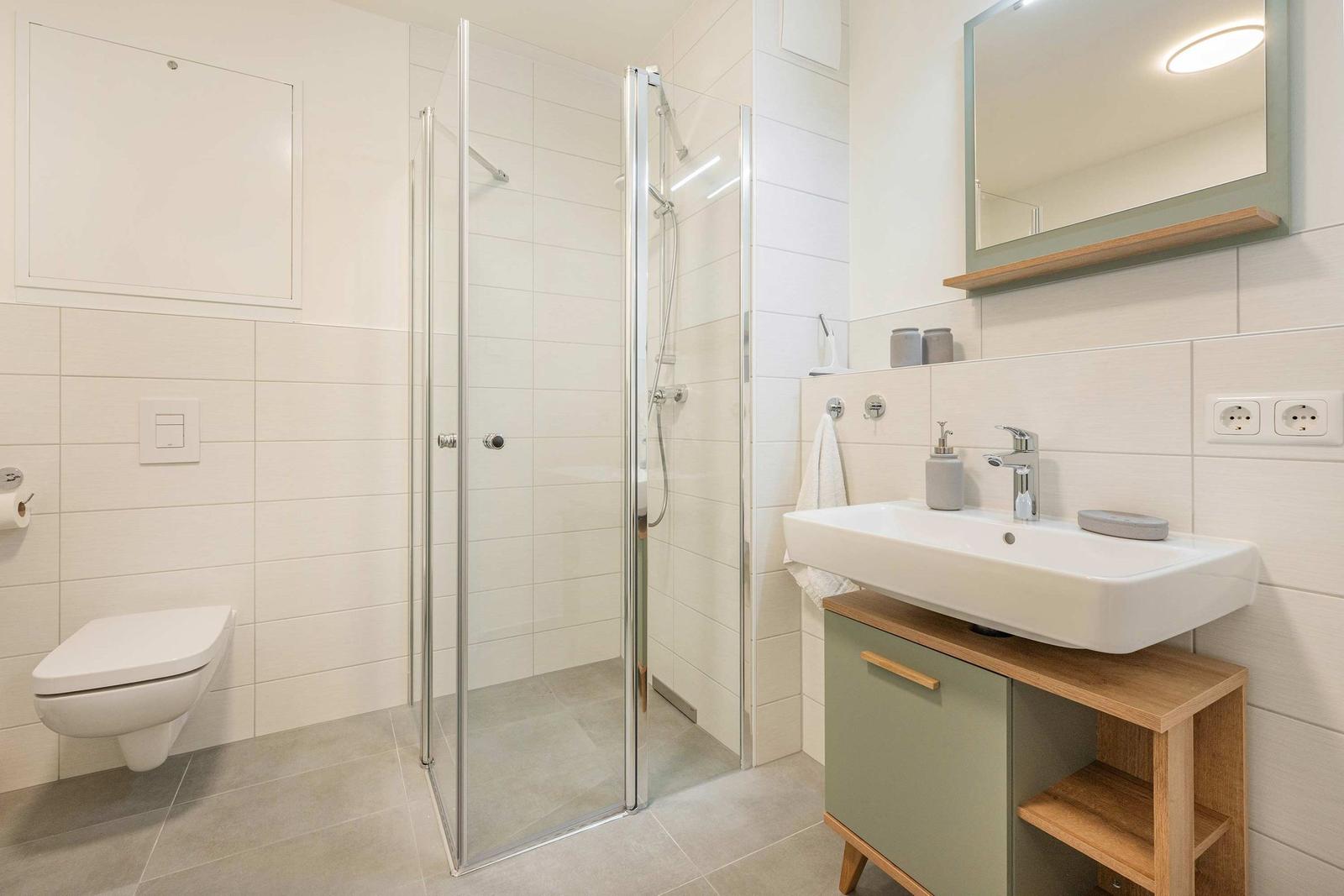 Bad mit Dusche, Waschbecken und Toilette. Moderne Einrichtung.