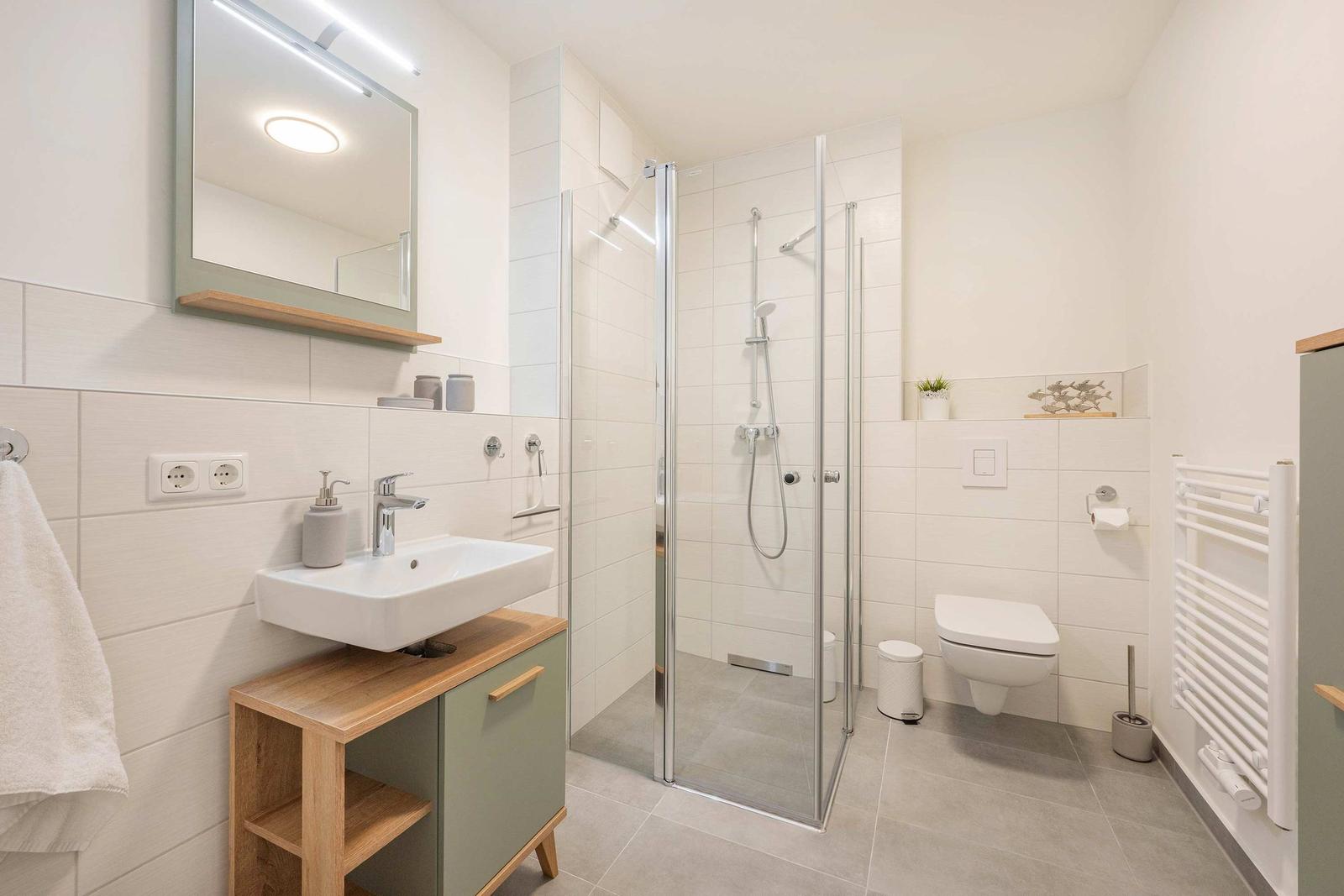Badezimmer mit Dusche, Waschbecken und Toilette. Moderne Einrichtung mit Holz- und Metallakzenten.
