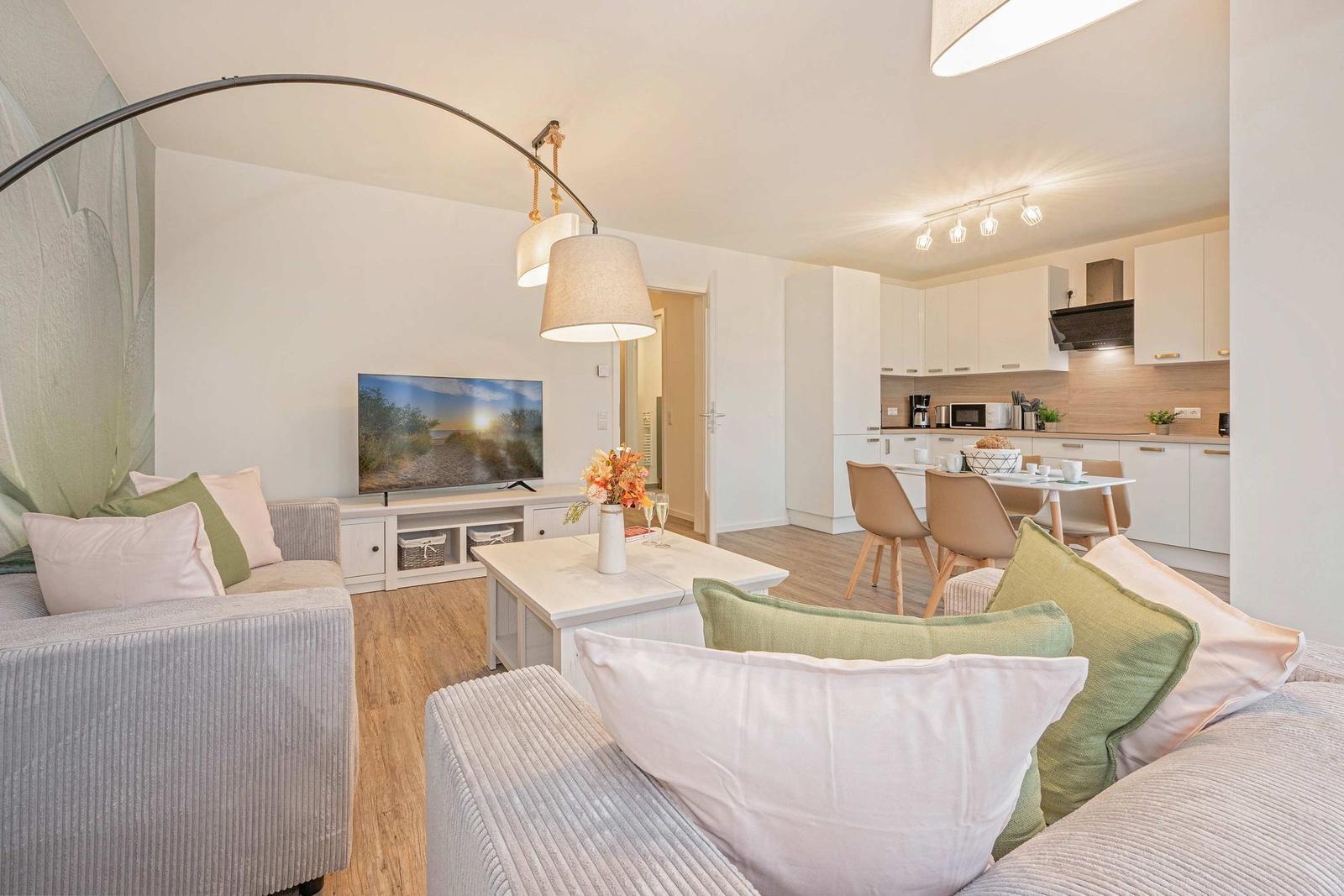 Wohnzimmer mit Sofa, Fernseher und Essbereich mit Tisch und Stühlen.