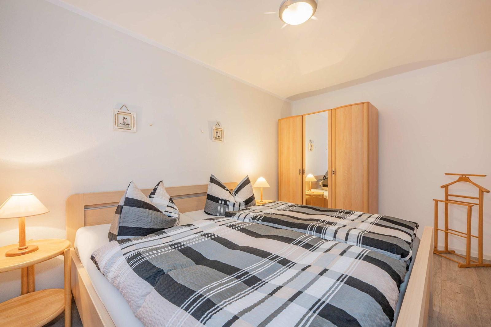 Schlafzimmer mit Doppelbett, Kleiderschrank und Nachttisch mit Lampe.