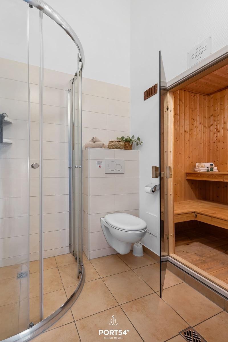 Shower, toilet and sauna in one room. Wooden frame and tiled floor.