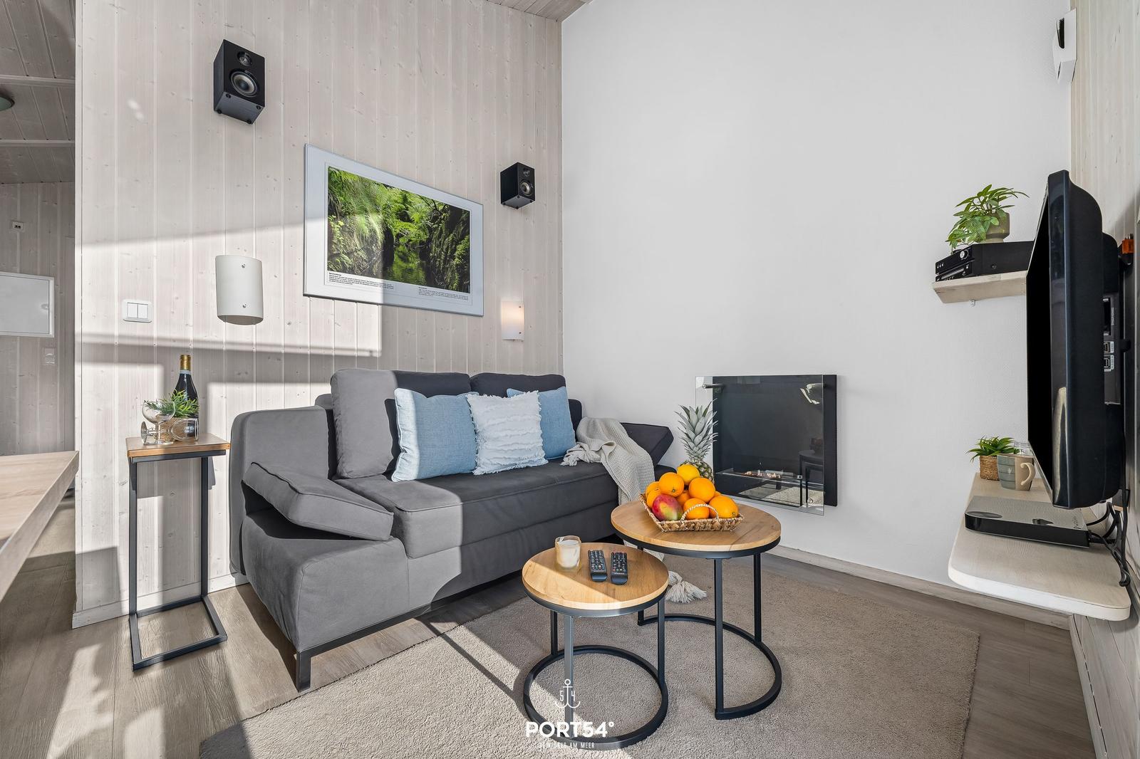 Living room with sofa, TV, and fireplace. Table with fruit and wall picture.